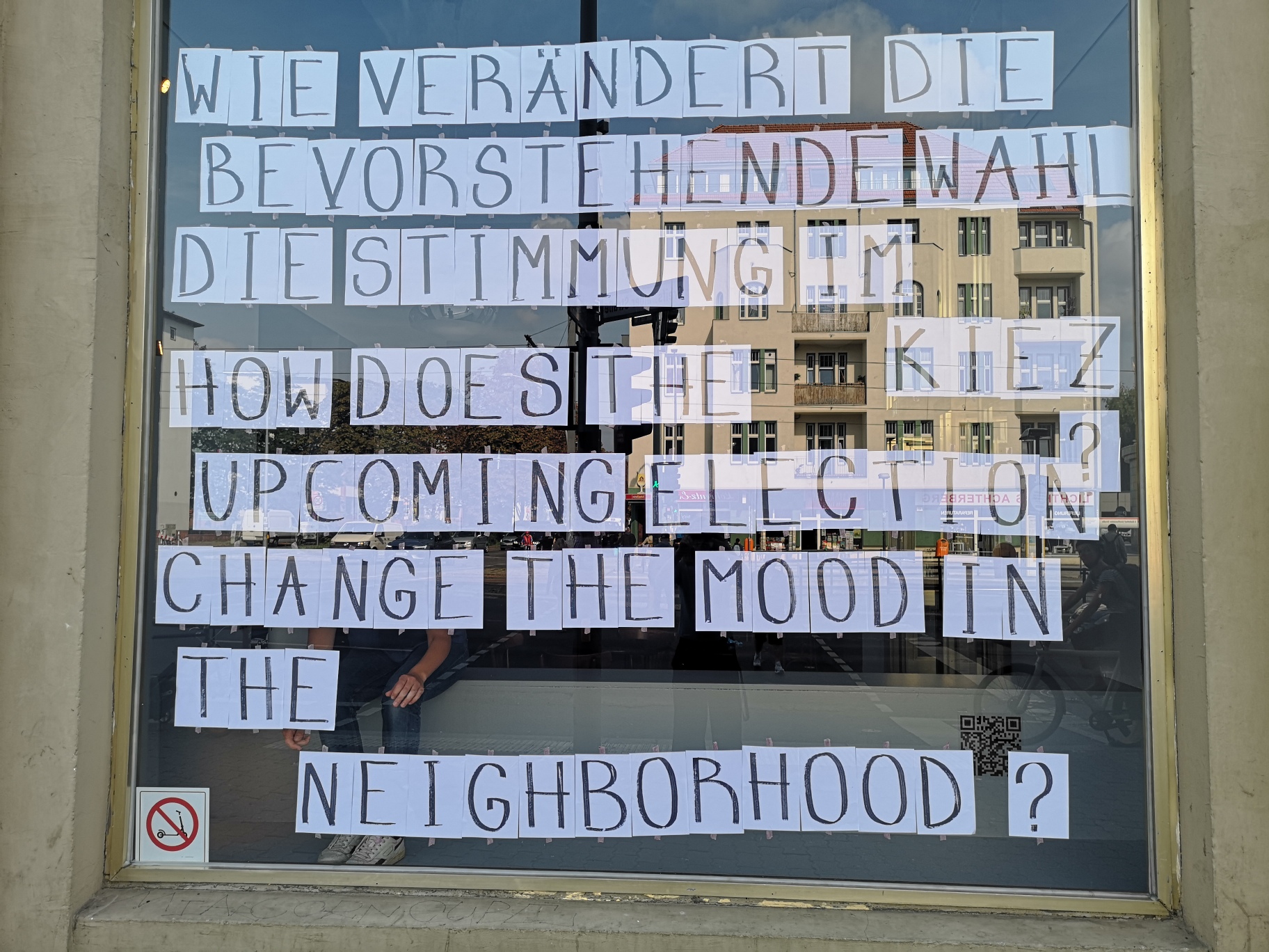 Schaufenster der Schaubude, auf dem auf einzelne Din-A4-Zetteln geschriebene Buchstaben zusammen die Frage ergeben: Wie verändert die bevorstehende Wahl die Stimmung im Kiez?