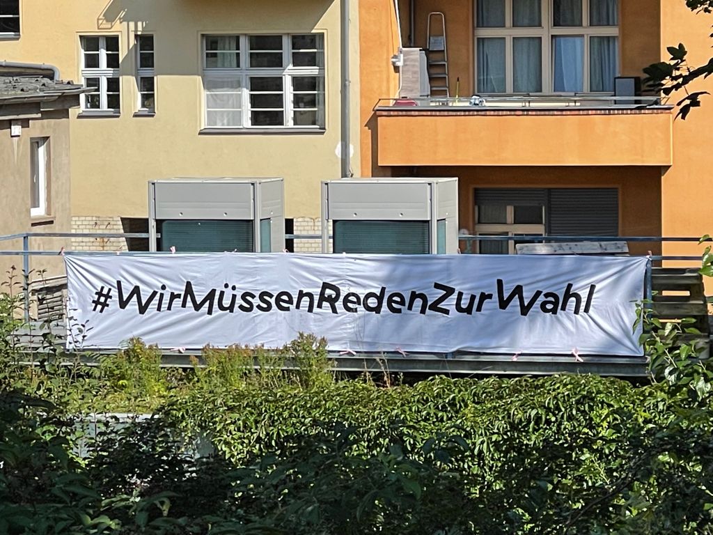 Banner auf dem Dach der Schaubude: #WirMüssenRedenZurWahl