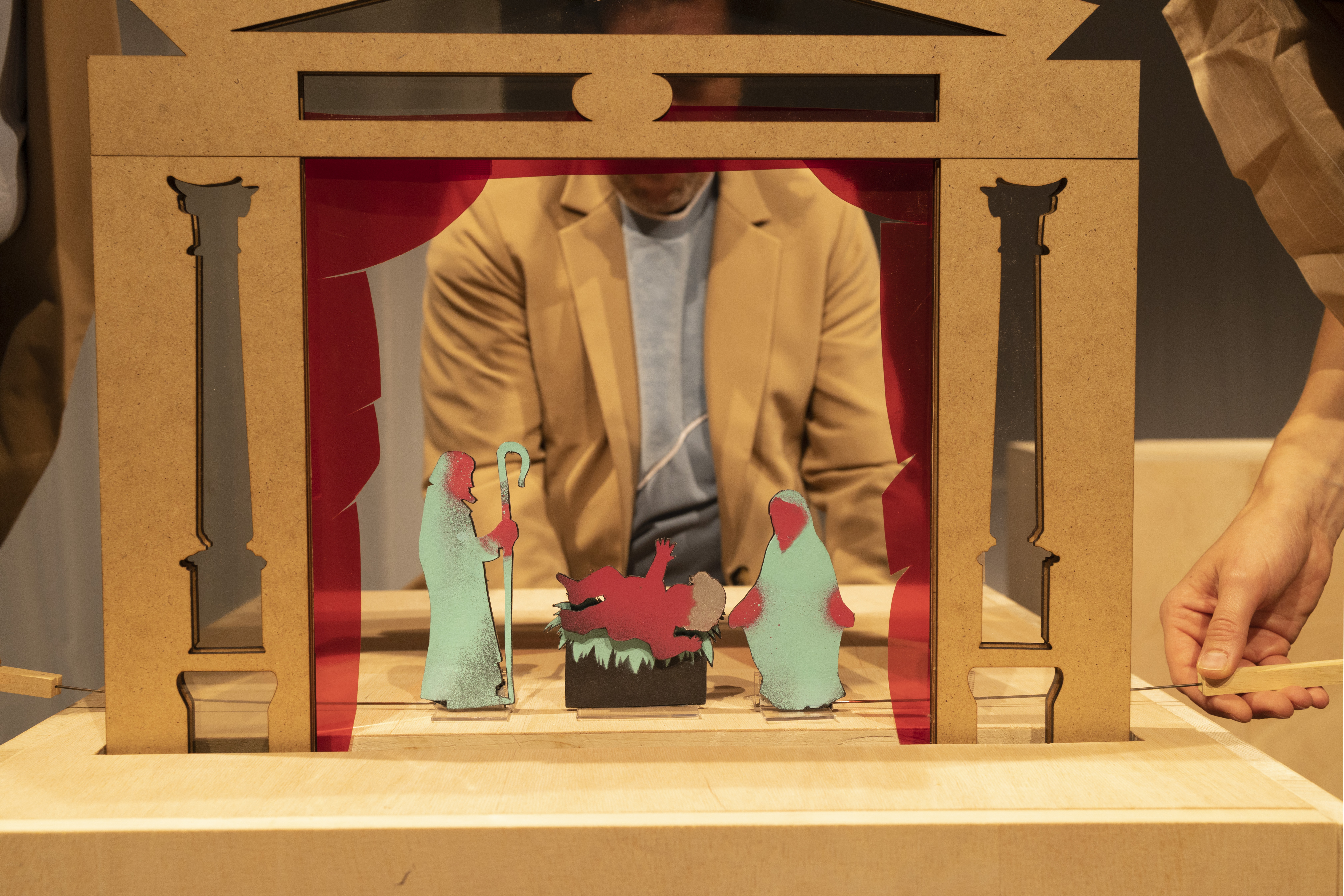 Kleine Flachfiguren in einer Miniatur-Theaterfassade aus Holz.