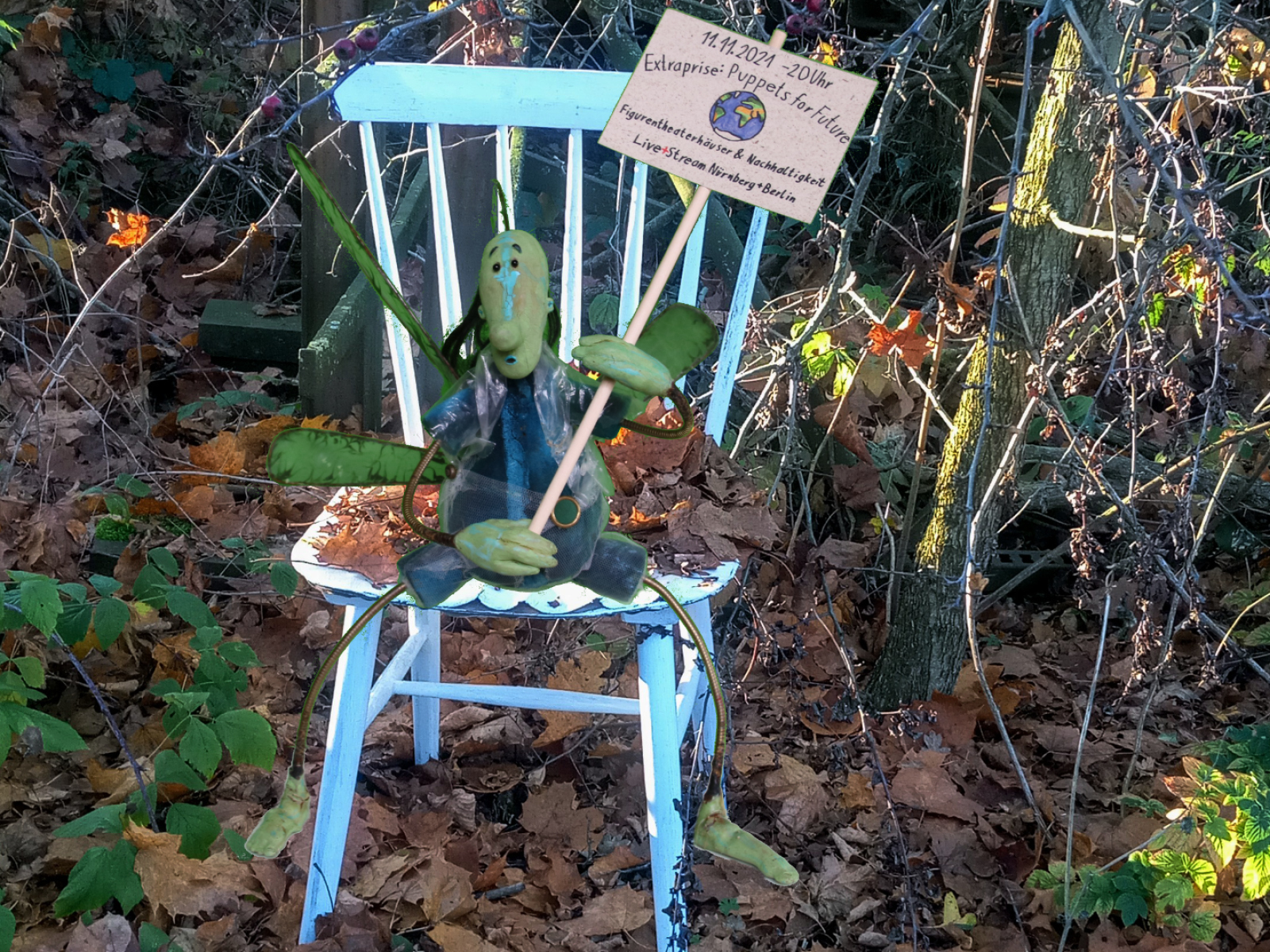 Stuhl mit einer kleinen grünen Puppe, die ein Protestschild hochhält