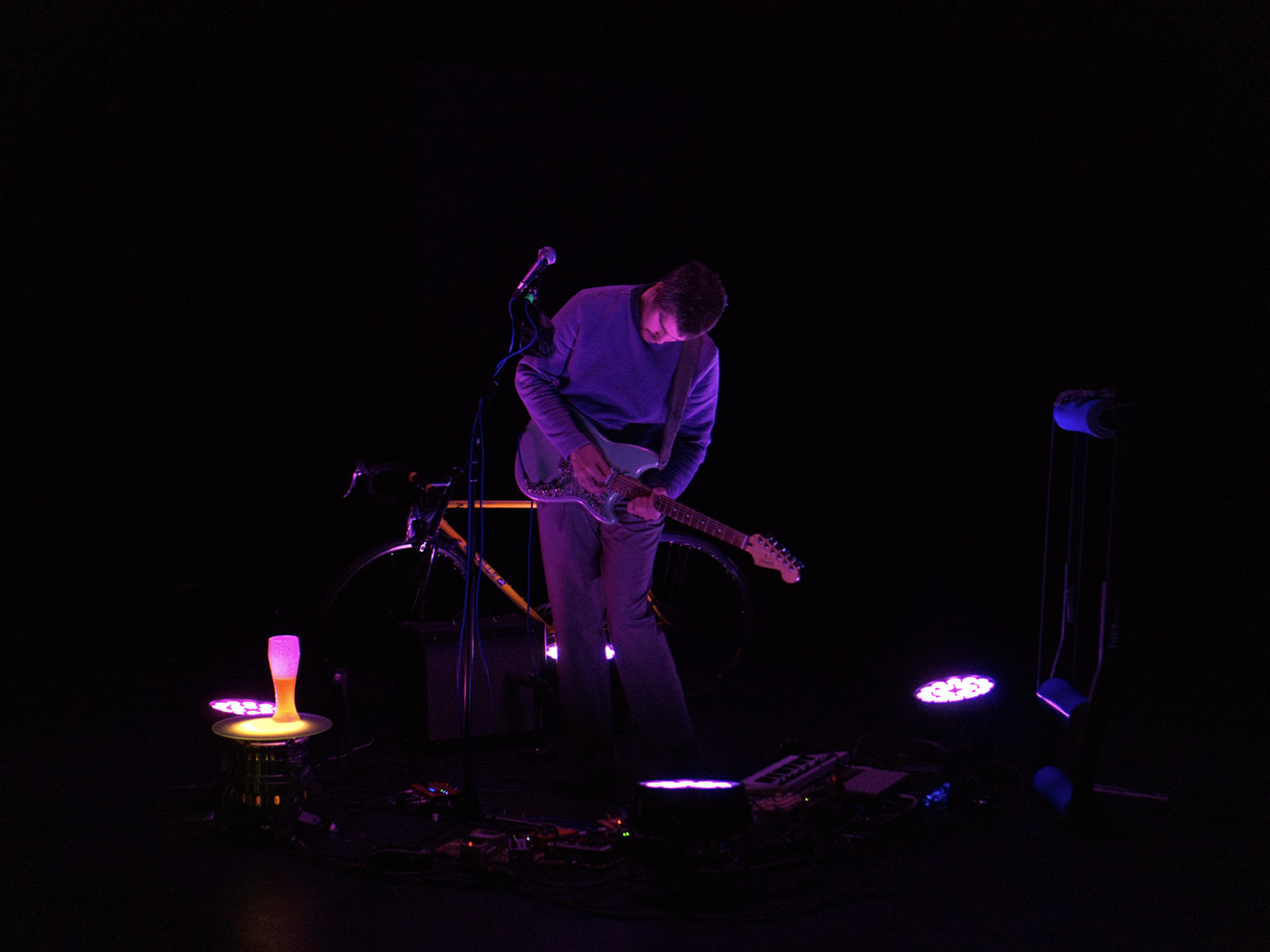 Einzelner Spieler auf dunkler Bühne mit E-Gitarre.