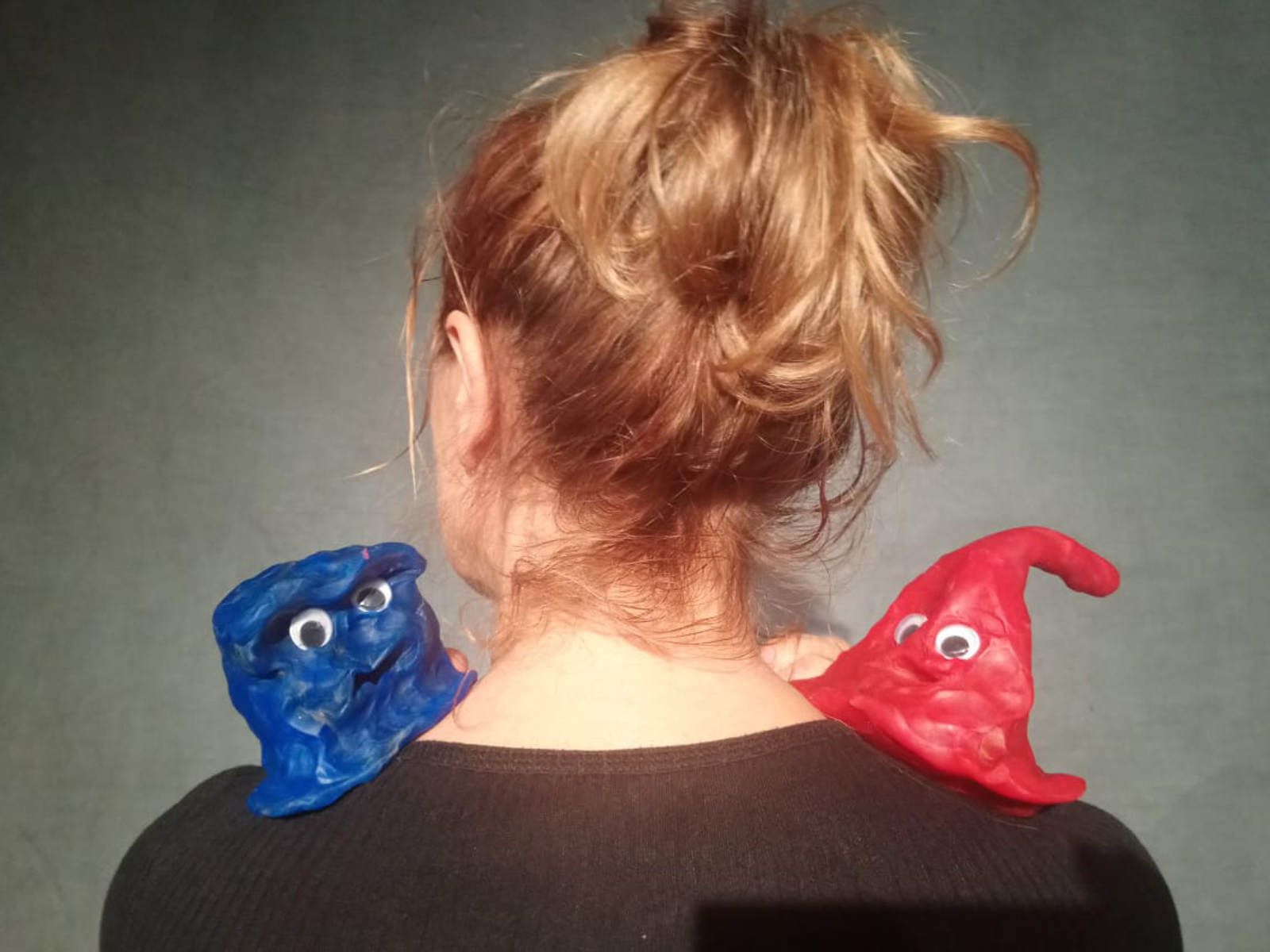 Ein blaue und eine rote Knetfigur mit Augen auf der Schulter einer Spielerin.