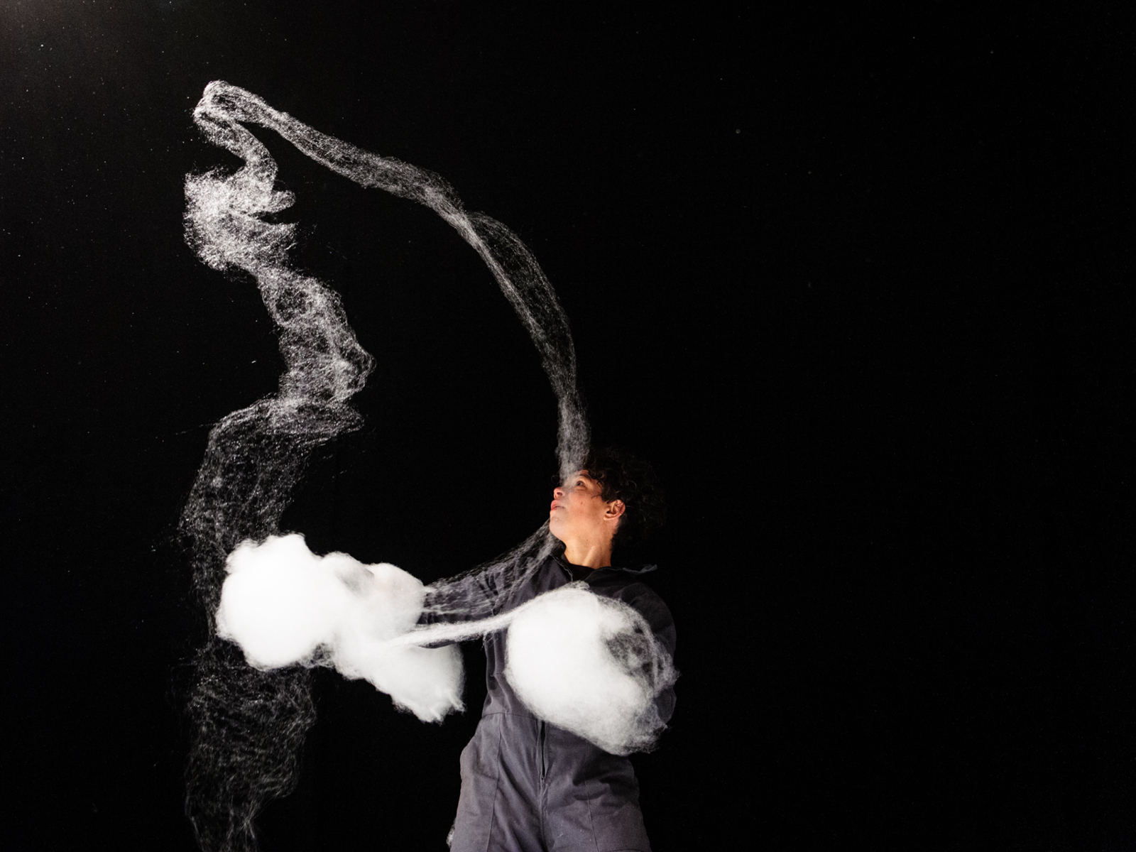 Performerin bewegt Zuckerwatte in der Luft über sich.