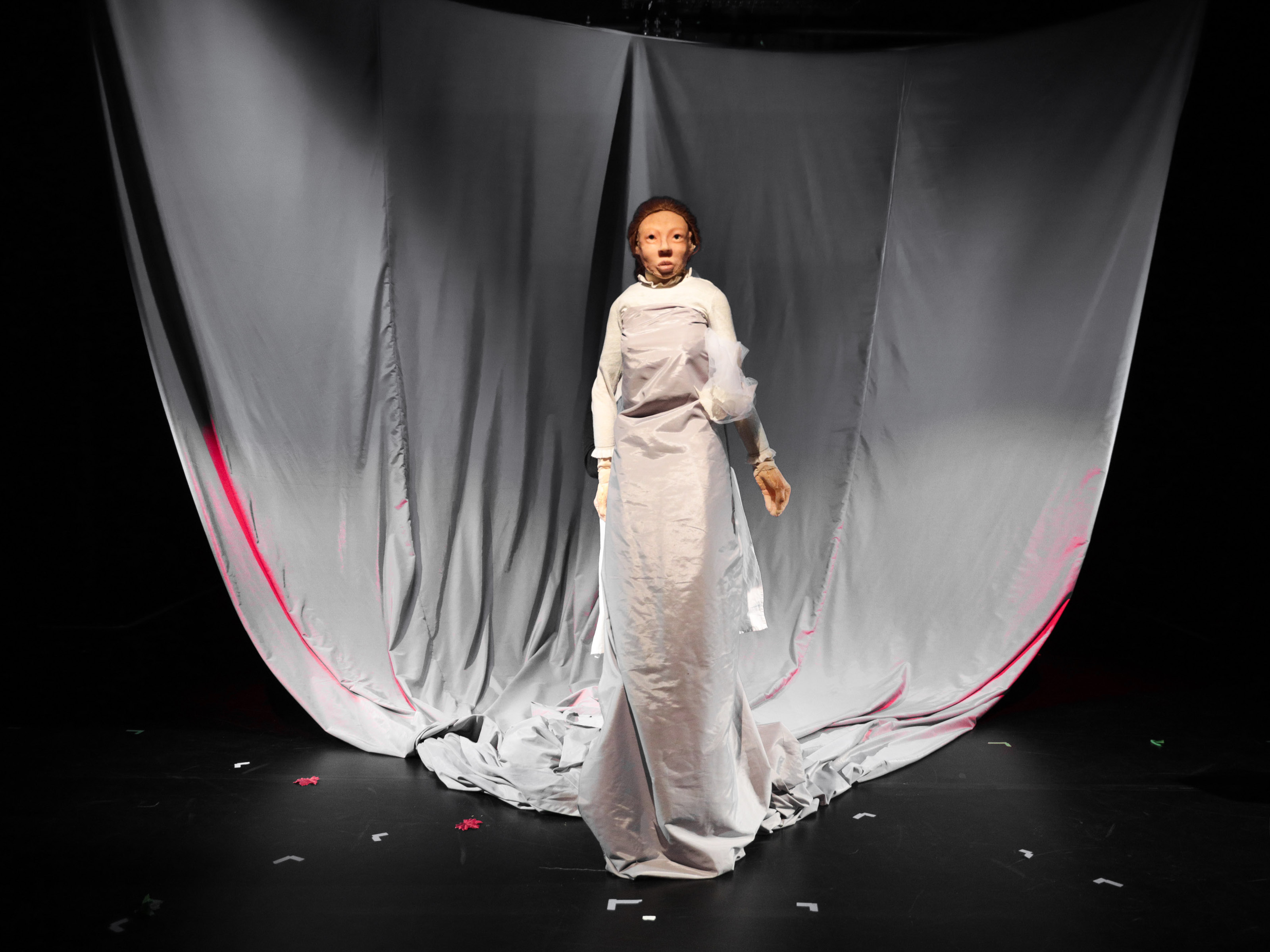 Helga's doll is wrapped in ghostly, slightly transparent white cloth. She wears a white KLeid and floats over the stage floor.
