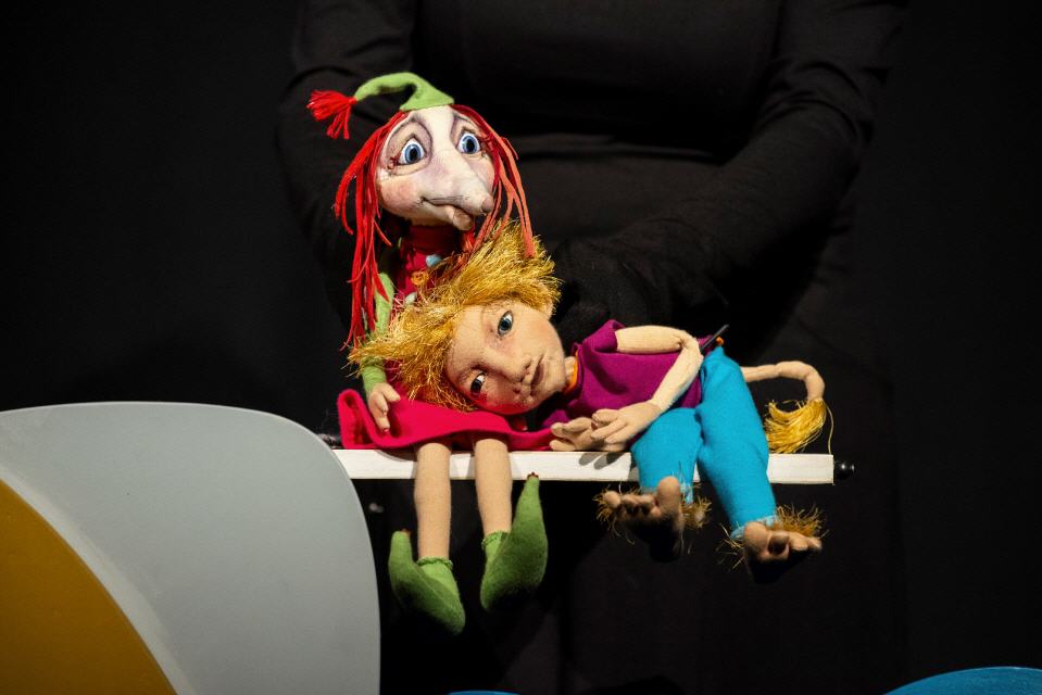 Zwei Puppen. Die eine stellt einen kleinen Jungen dar, der seinen Kopf in den Schoss der zweiten Puppe legt, die ein Troll ist.