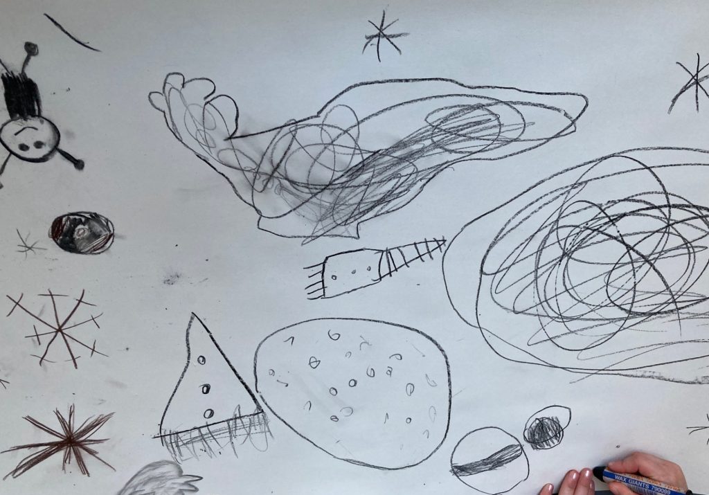 auf weißem papier sind mit schwarzem Stift gekritzelte Kreise, eine Rakete, Sterne und runde Formen mit Punkten zu sehen, die an Himmelskörper erinnern sollen