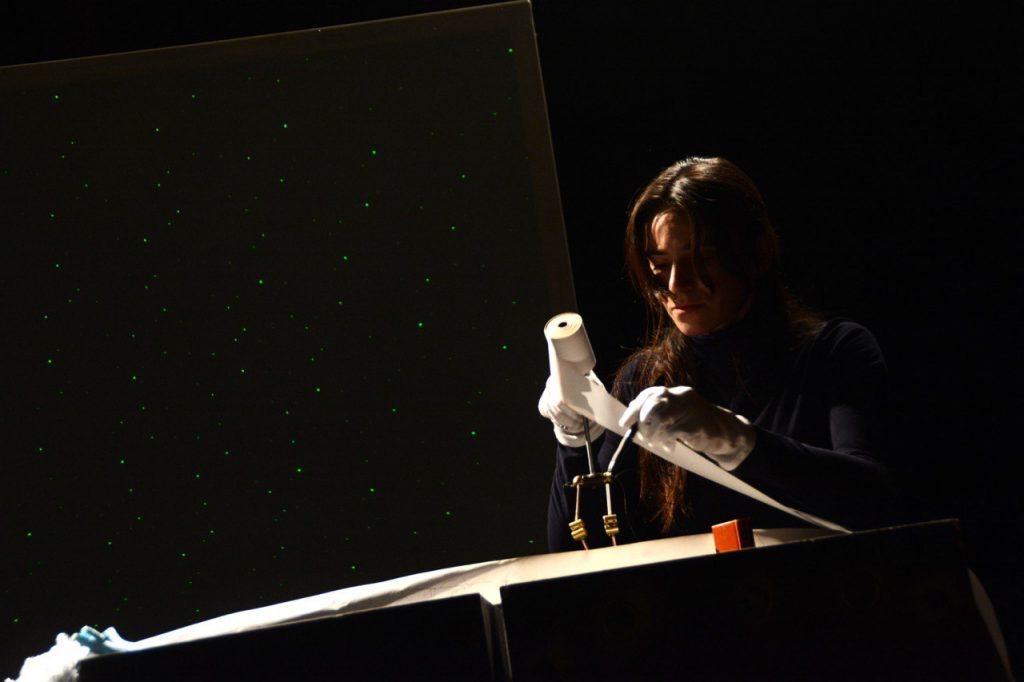 Eine junge Frau hält eine Papierrolle in der einen Hand und zwei Metallbeine in der anderen Hand und animiert die Figur.