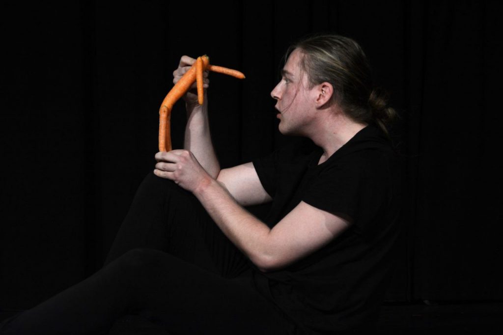 Ein junger Mann hält eine Figur vor sein Gesicht. Sie scheint ihn anzublicken.