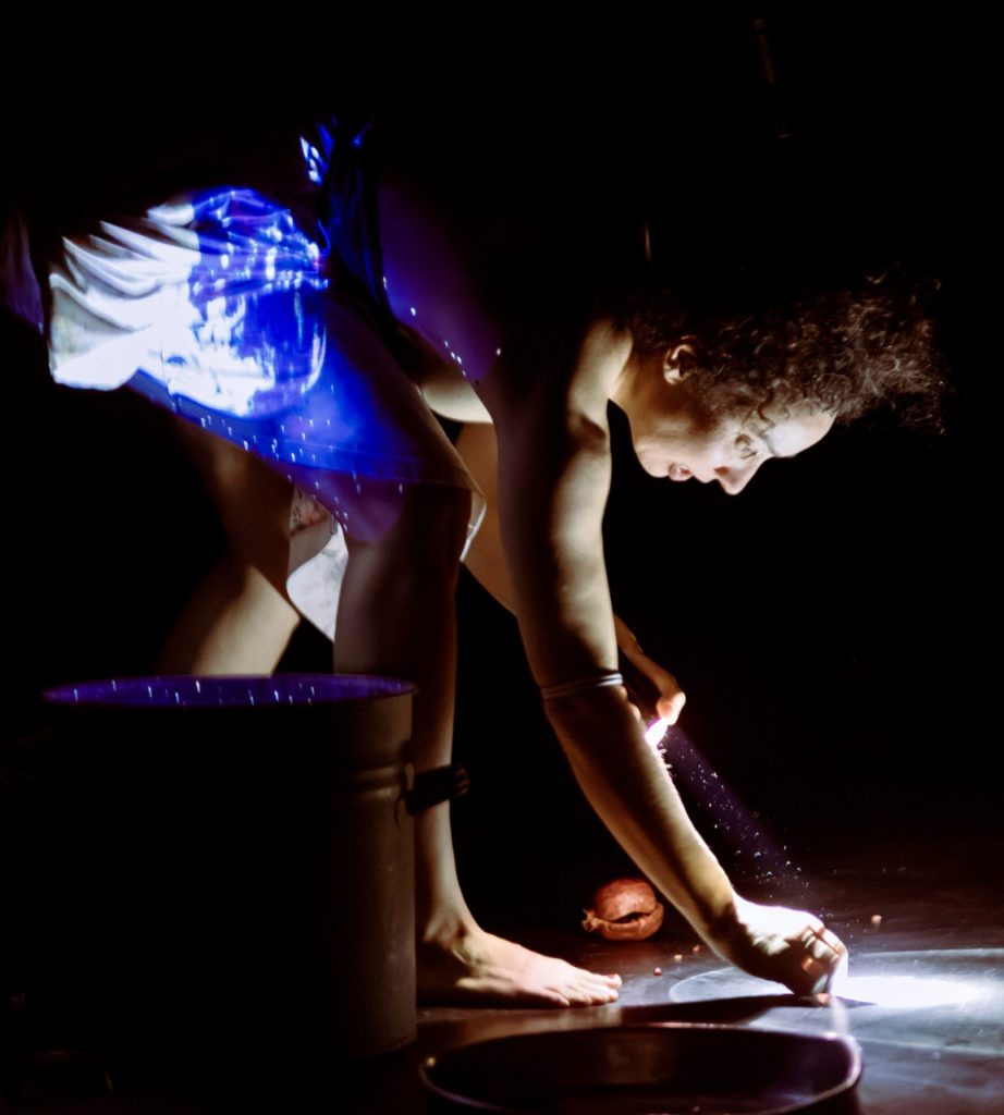 Eine junge Frau beugt sich zum Boden. Auf ihr ist eine Beamer Projektion