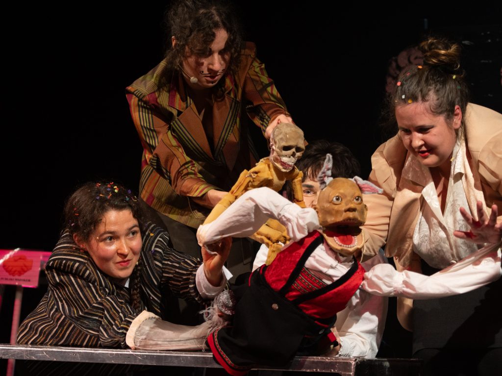 Drei Studierende führen eine Klappmaulpuppe.