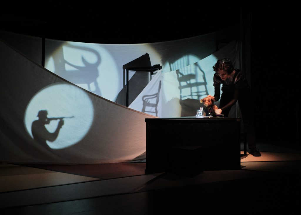 Schattentheater mit projizierten Objekten und Person hinter einer Leinwand.
