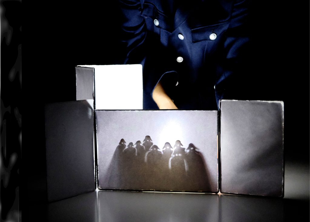 Schattenspiel mit silhouettierten Figuren hinter einer beleuchteten Leinwand.